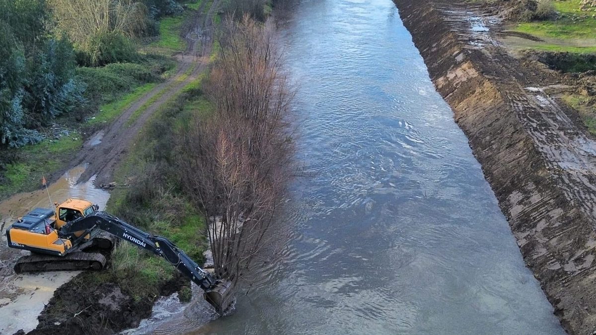 Cauce encauzado con excavadora trabajando en la ribera